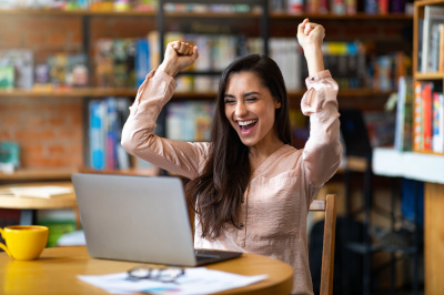 Woman cheering in front of laptop