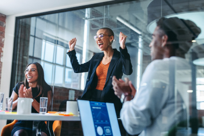 Cheerful young businesswoman smiling while being applauded by her colleagues in a modern office. Happy young businesswoman receiving praise from her team during a meeting.